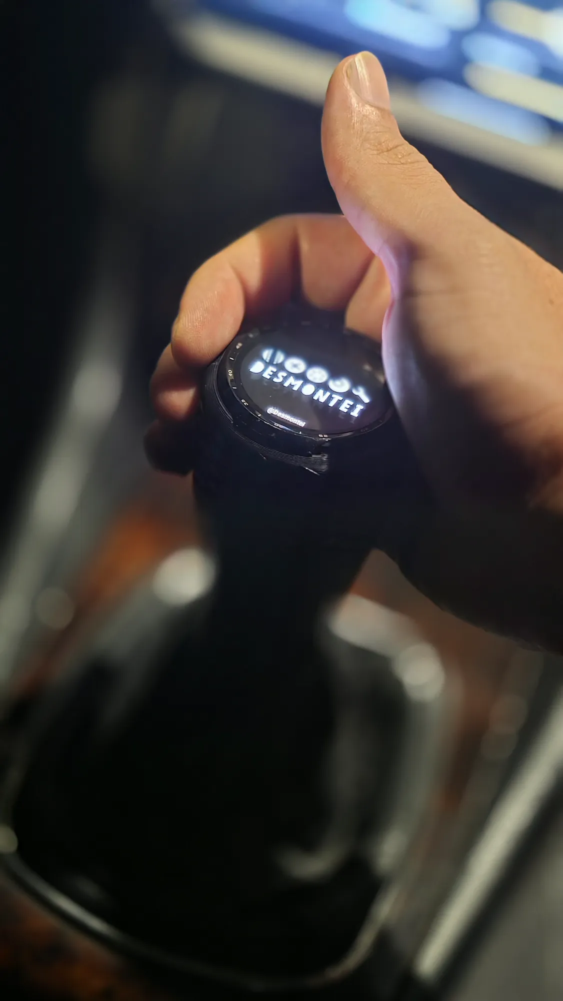 Hand shifting gears on the new digital shift knob with the Desmontei logo on screen